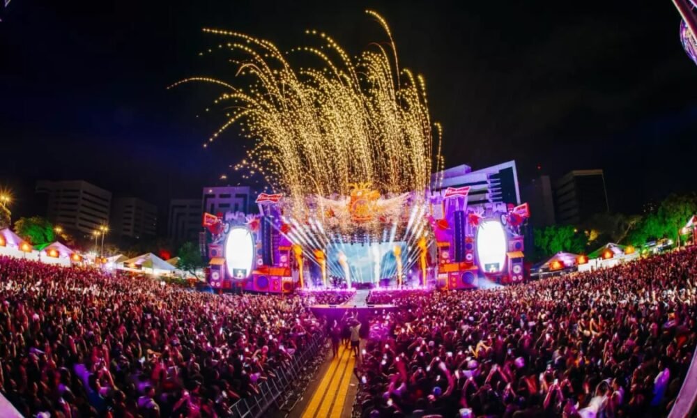Público lota o Rap In Cena 2025 no Parque Harmonia, em Porto Alegre, com palco iluminado e fogos durante o festival.