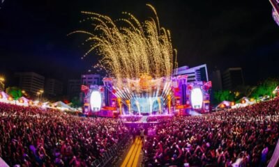 Público lota o Rap In Cena 2025 no Parque Harmonia, em Porto Alegre, com palco iluminado e fogos durante o festival.