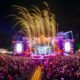 Público lota o Rap In Cena 2025 no Parque Harmonia, em Porto Alegre, com palco iluminado e fogos durante o festival.