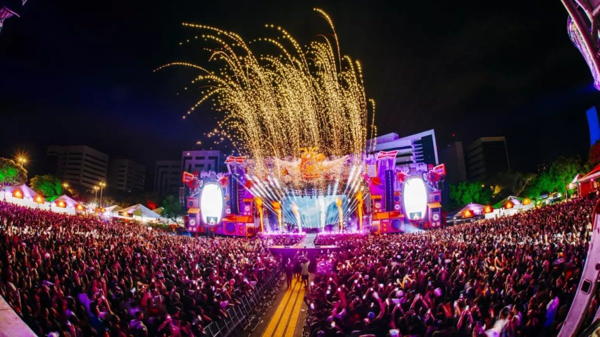 Público lota o Rap In Cena 2025 no Parque Harmonia, em Porto Alegre, com palco iluminado e fogos durante o festival.