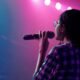 Mulher com microfone em apresentação de rap representa o evento Elas na Batalha em Goiânia