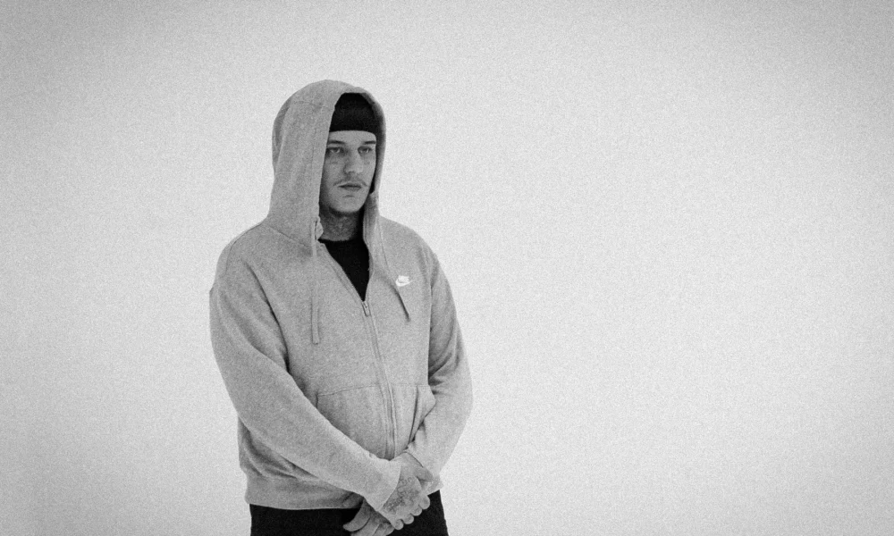 Rapper 2T de moletom cinza com capuz, em ensaio em preto e branco do projeto FRAGMENTTADO