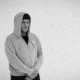 Rapper 2T de moletom cinza com capuz, em ensaio em preto e branco do projeto FRAGMENTTADO