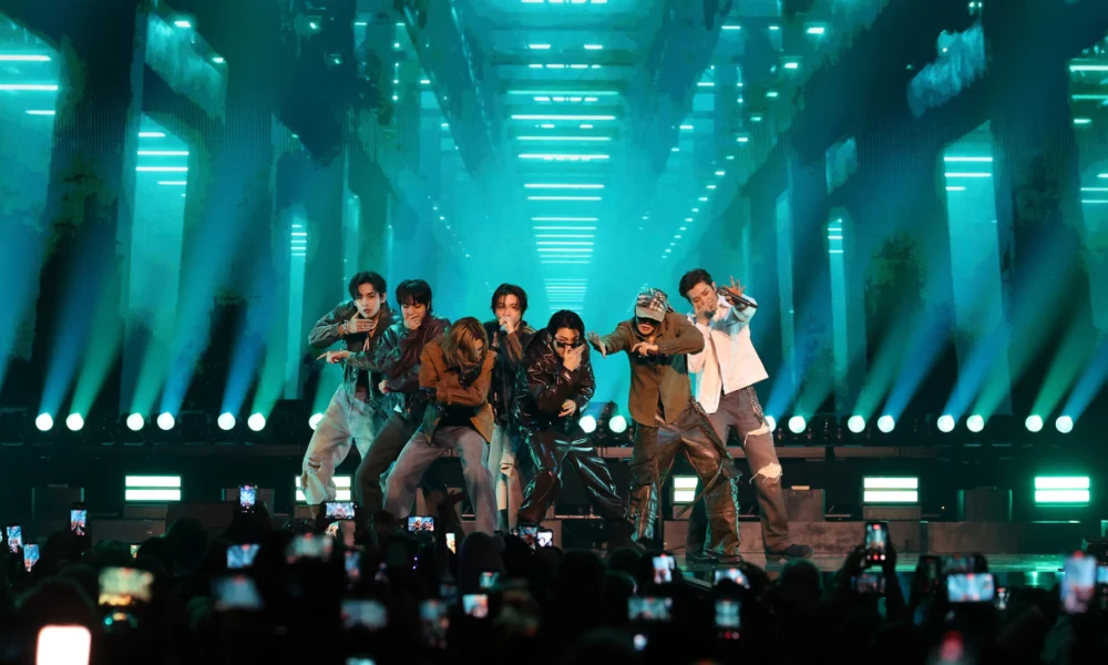 Os sete integrantes do BTS se apresentam em palco iluminado de verde diante do público