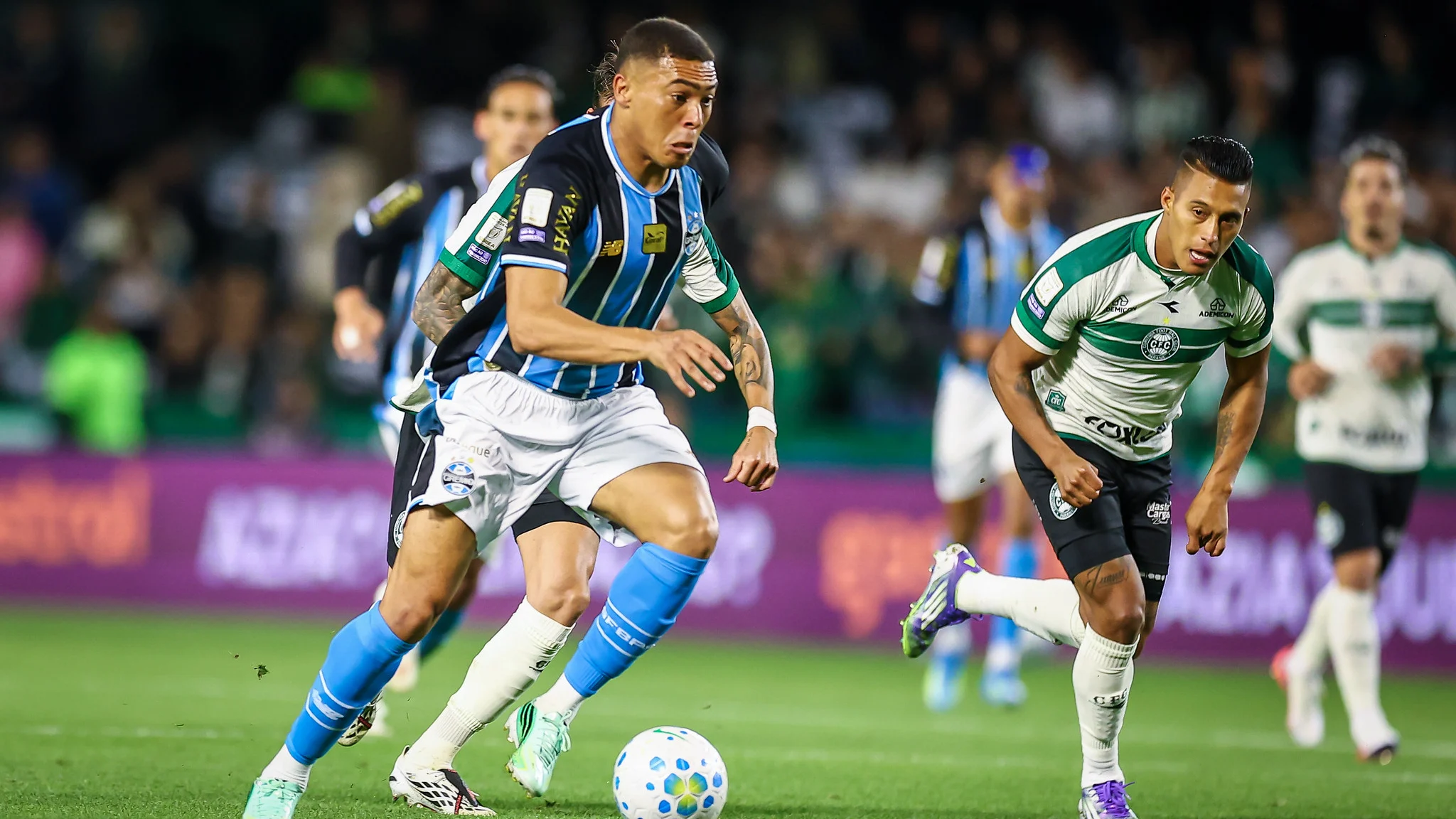 Jogador do Grêmio conduz a bola marcado por atleta do Coritiba no Couto Pereira