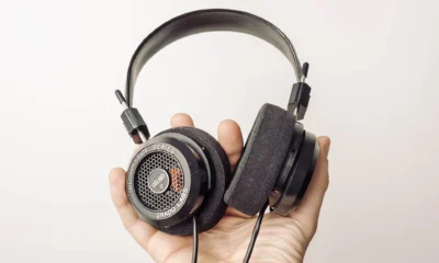 Mão segura fones de ouvido sobre fundo claro, imagem ilustrativa de streaming de música