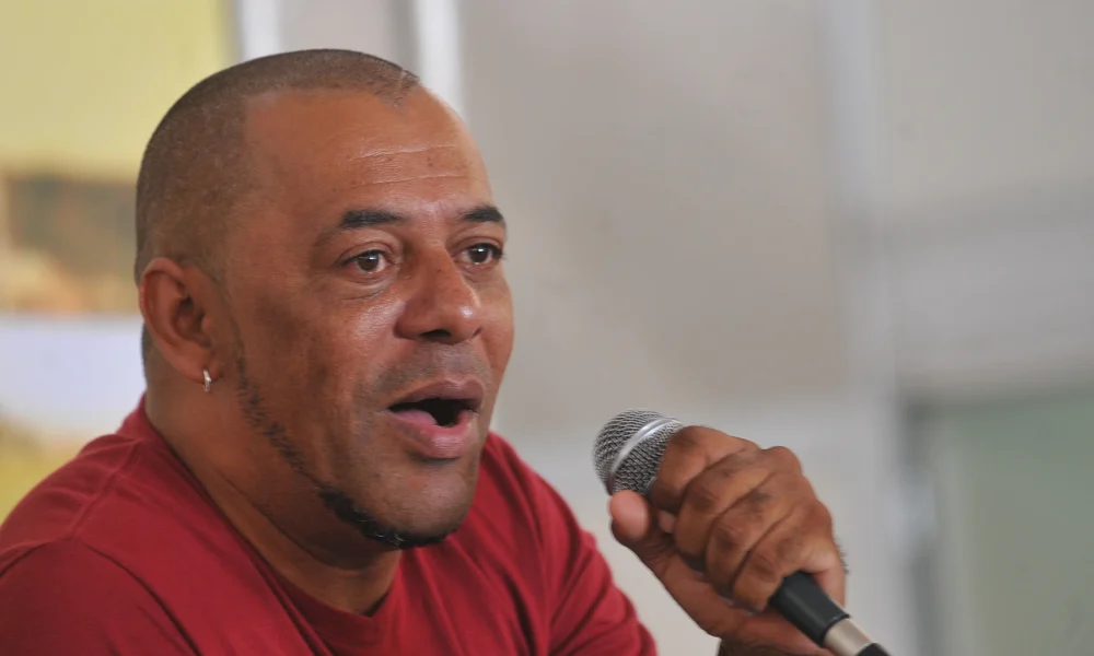 O rapper GOG, de camiseta vermelha, fala ao microfone em debate em Brasília