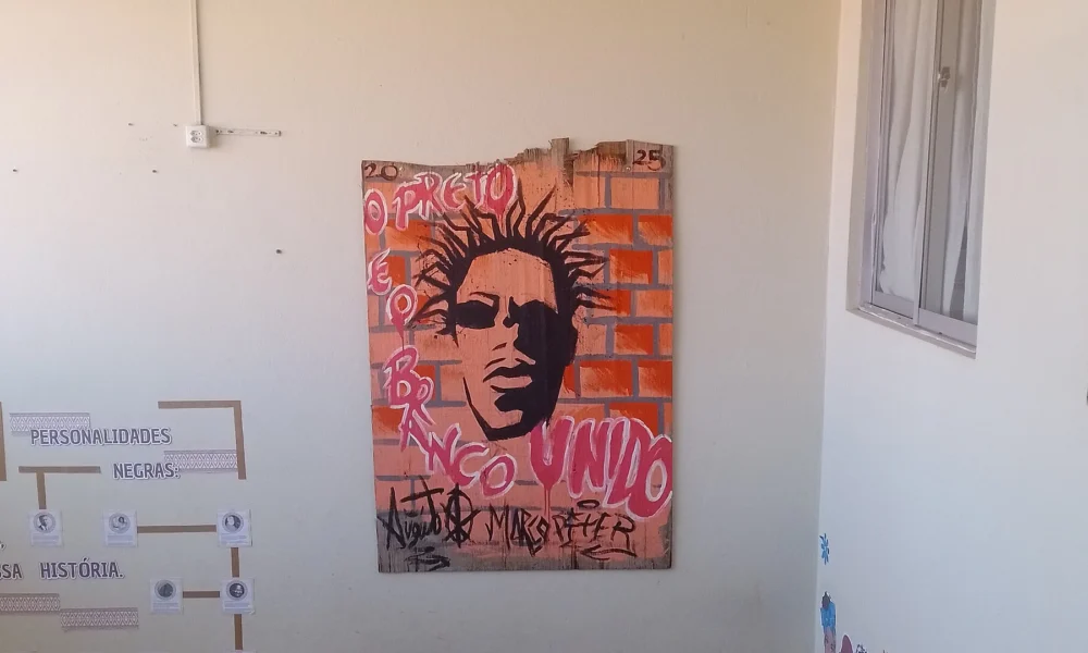 Painel grafitado com o rosto de Sabotage fixado em parede de corredor
