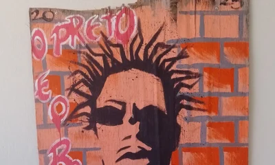 Grafite com o rosto do rapper Sabotage pintado sobre tijolos laranja, com letras cor-de-rosa