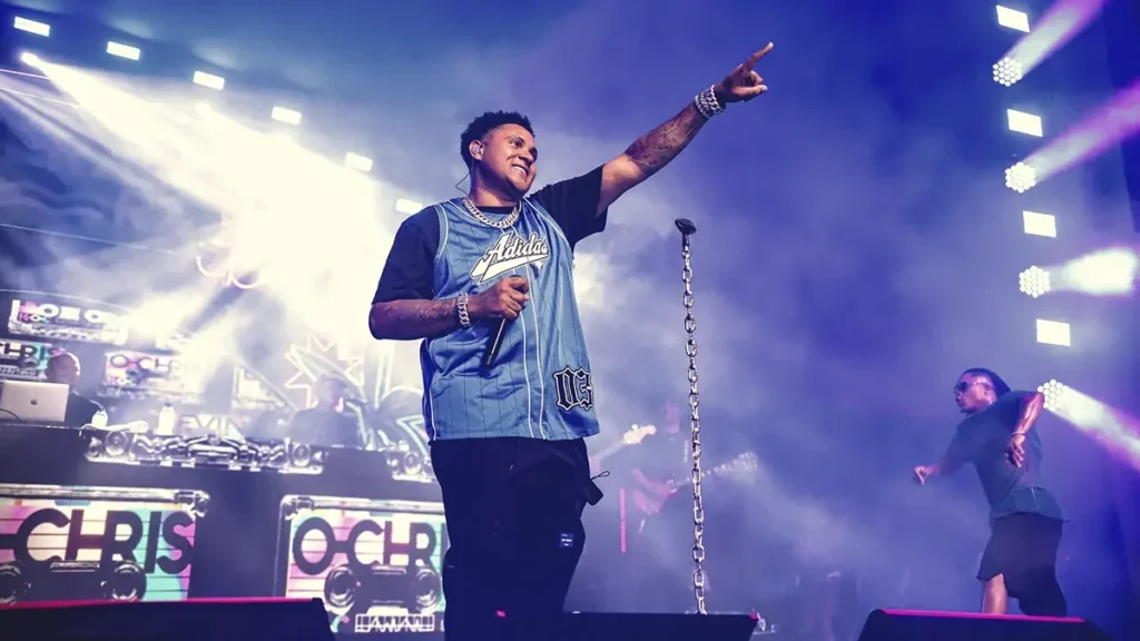 Kevin O Chris aponta para o público em show com luzes azuis e telão com seu nome