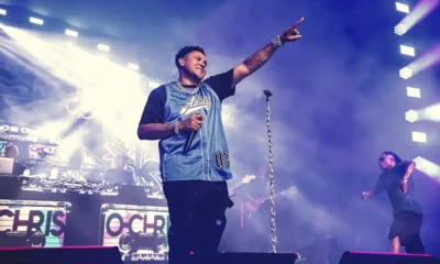 Kevin O Chris aponta para o público em show com luzes azuis e telão com seu nome
