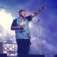 Kevin O Chris aponta para o público em show com luzes azuis e telão com seu nome