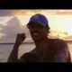 MC Livinho de boné azul em praia ao pôr do sol no clipe de Azul Piscina 2