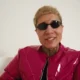 Massaru de óculos escuros e jaqueta vermelha em cena do clipe de Obito