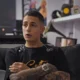 MC Hariel dá entrevista sentado em sofá em cena do documentário Melhores Dias