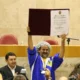 Nelson Triunfo, de touca de crochê e agasalho azul, ergue o diploma de Cidadão Paulistano na Câmara Municipal de São Paulo