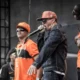 Integrantes dos Racionais MC's no palco da Virada Cultural de São Paulo, com camisas laranja e jaqueta jeans