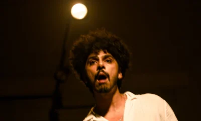 O ator Rafael Cristiano, de camisa branca, em cena sob luz baixa no espetáculo do Grupo II