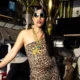 Rapper CAE de óculos redondos e vestido de oncinha posa em bar em foto de divulgação