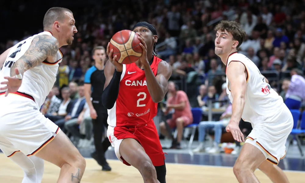 Shai Gilgeous-Alexander, com a camisa 2 do Canadá, conduz a bola entre dois jogadores da Alemanha em amistoso de 2023