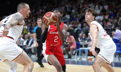 Shai Gilgeous-Alexander, com a camisa 2 do Canadá, conduz a bola entre dois jogadores da Alemanha em amistoso de 2023