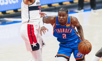 Shai Gilgeous-Alexander com o uniforme azul do Oklahoma City Thunder conduzindo a bola em jogo da NBA