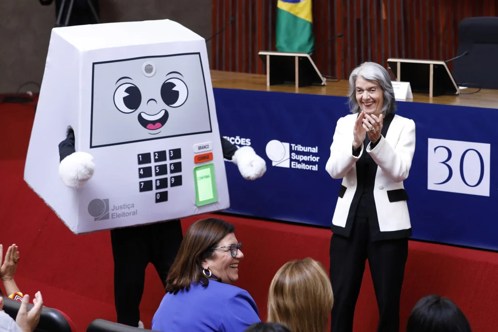 Mascote da urna eletrônica e público em evento dos 30 anos da urna no TSE