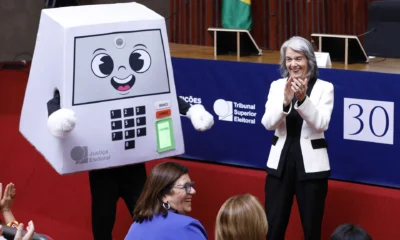 Mascote da urna eletrônica e público em evento dos 30 anos da urna no TSE