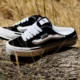 Tênis Vans Knu Skool Mule da coleção VANSZA, em preto e branco, apoiado num tronco ao ar livre