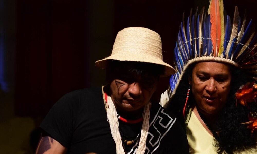Duas pessoas indígenas com adornos tradicionais em atividade cultural; imagem de divulgação da Virada Indígena 2026.